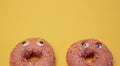 Two glazed pink donuts isolated with funny faces