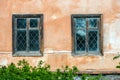 Two glazed Windows with reflections on the glass in the Windows are inserted bars from burglars on the old cracked orange wall Royalty Free Stock Photo