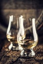 Two Glencairn whisky tasting glasses on vintage wood and dark wooden barrel in the back