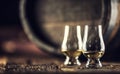 Two Glencairn whisky tasting glasses on vintage wood and dark wooden barrel in the back