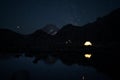 Two glowing tents in high mountains at night under starry sky