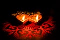 Two glowing terracotta lamps against dark background in Diwali concept
