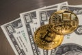 Two gold coins bitcoin lie on hundred dollar bills, photo close-up