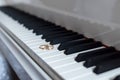 Two gold rings lie on the keys of white piano Royalty Free Stock Photo