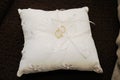 Two gold rings on a small white cloth embroidered cushion.
