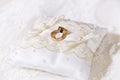 Two gold shiny wedding rings together on satin lace pillow Royalty Free Stock Photo