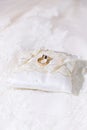 Two gold shiny wedding rings together on satin lace pillow Royalty Free Stock Photo