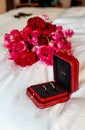 21 June 2021. Two gold wedding rings Cartier on the background of a wedding bouquet, in a red box. Holiday. Pink flowers