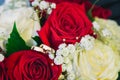 Two gold wedding rings lie on the bridal bouquet composed of white and red roses Royalty Free Stock Photo