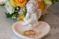 Two gold wedding rings lie on a platter in a rose shape with the angel sculpture near bouquet of orange roses and whit Royalty Free Stock Photo