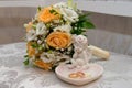 Two gold wedding rings lie on a platter in a rose shape with the angel sculpture near the bride's bouquet Royalty Free Stock Photo