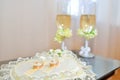 Two gold wedding rings on pillow with glasses of champagne Royalty Free Stock Photo