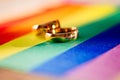 Two gold wedding rings on rainbow lgbt flag. Homosexual marriage