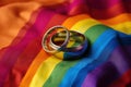 Two gold wedding rings on rainbow lgbt flag. Homosexual marriage