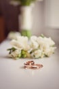 Two gold wedding rings with on a white background with a wedding bouquet Royalty Free Stock Photo