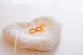 Two gold wide wedding rings on a white decorative pillow decorated with white lace and beads on a light background Royalty Free Stock Photo