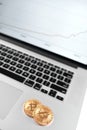 Two golden bitcoins placed on silver laptop with financial chart on its screen.