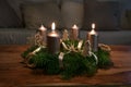 Two golden candles are lit for the second Sunday on an Advent wreath wth natural Christmas decoration on a wooden coffee table,