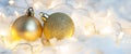 Two golden Christmas balls on background of garland shining lights and snow, banner with copy space Royalty Free Stock Photo