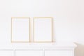 Two golden vertical frames on white furniture, luxury home decor and design for mockup creation