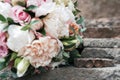 Two golden wedding rings on stone near   beautiful wedding bouquet of white and pink peony and roses in blur outdoors Royalty Free Stock Photo