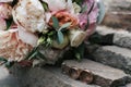 Two golden wedding rings on stone near   beautiful wedding bouquet of white and pink peony and roses in blur outdoors. Royalty Free Stock Photo