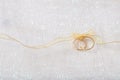 Two golden wedding rings tied with a golden ribbon on white shiny background Royalty Free Stock Photo