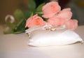 Golden wedding rings on a white pad near pink roses bouquet Royalty Free Stock Photo