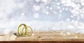 Two golden wedding rings on wooden table, blur snowy background, copy space, 3d illustration Royalty Free Stock Photo