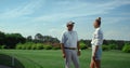 Two golfers talking sport on course field. Golf players chat on fairway grass. Royalty Free Stock Photo