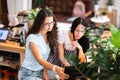 Two good looking young girls with long dark hair,wearing casual style,sit at the table and look attentively at the Royalty Free Stock Photo