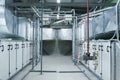 Two gray industrial air handling units in the ventilation plant room with big size ductworks and pipelines