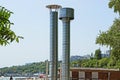 Two gray metal chimney pipes against the sky and green branches