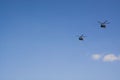 Two gray military helicopters fly in the blue sky. Demonstration of a peaceful flight. Day of the city. Memory. Air show