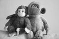 Two gray toy monkeys are sitting in an embrace.