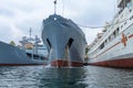 Two gray warships of the Russian Navy and a white hospital ship in port on the Black Sea.