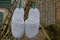 Two gray woolen slippers dry on a wire on clothespins