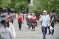 Two Greek Red Cross personel cycle along a street amongst people walking in both directions