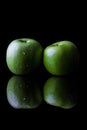 Two green apples on black from side with reflection vertical Royalty Free Stock Photo