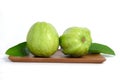 Two green crystal guava fruit with leaves on a wooden plate isolated on white background Royalty Free Stock Photo