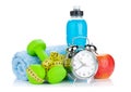 Two green dumbells, tape measure, healthy food and alarm clock