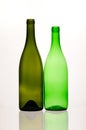 two green and empty wine bottles of different sizes and forms and their reflections Royalty Free Stock Photo