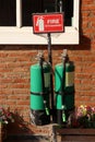 Two green fire extinguisher with the red sign and white text and symbolic icon on brick wall Royalty Free Stock Photo
