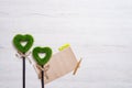 Two green grassy hearts, sheet of paper and pencil on a white wooden background Royalty Free Stock Photo