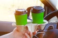 Two green paper cups with tea or coffee in a male hand in car on sunny blurred background. Takeaway, social media. Morning Royalty Free Stock Photo