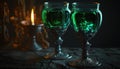 two green wine glasses sitting next to each other on a table next to a lit candle in a dark room wit Royalty Free Stock Photo