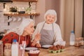 Two grey-haired ladies enjoying cooking in the modern kitchen