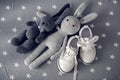 Two grey knitted toy rabbit and children`s white shoes Royalty Free Stock Photo