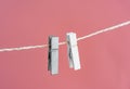 Two grey and white clothes pins on a clothes line rope holding nothing on a pink background Royalty Free Stock Photo