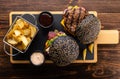 Two grilled burgers with beef cutlet, sauce and French fries on a wooden board, top view. Fast food set Royalty Free Stock Photo